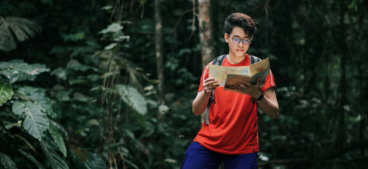 Young man with a map in the rainforest